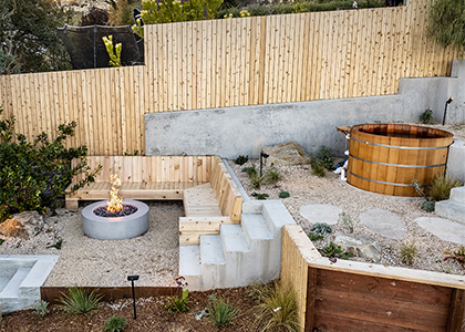 Landscaping construction project in a San Francisco hill close to Twin Peaks with level containing walls, wooden hot tub and a modern concrete fire pit